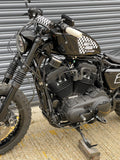 Close-up of a motorcycle parked on a textured surface with a metallic background